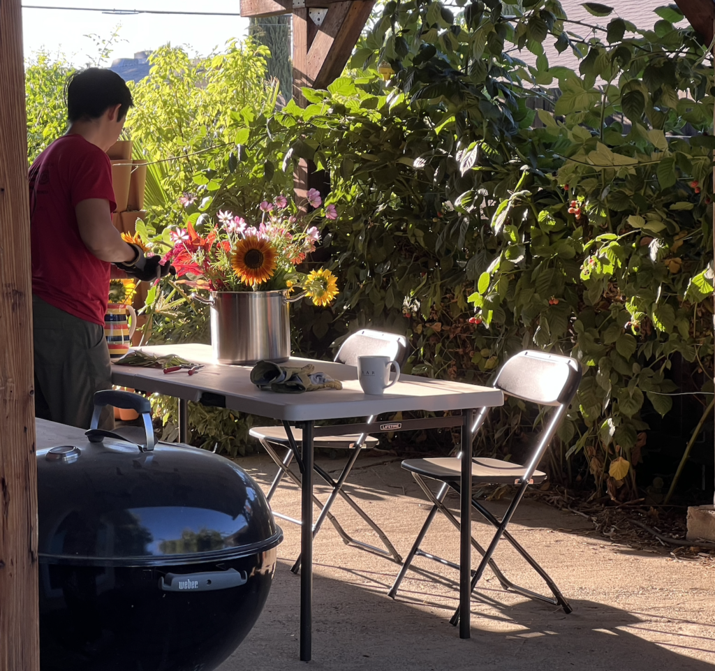 man making flower arrangement on patio table in backyard garden